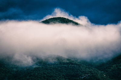 Mountain top breaking through the clouds in evening light