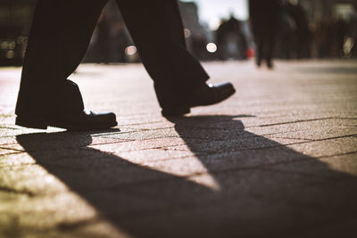 Low section of man walking on footpath in city