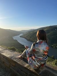 Rear view of woman looking at mountains against clear sky