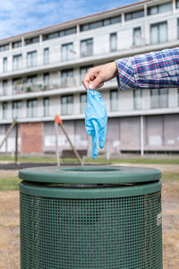 Cropped hand throwing glove in dustbin