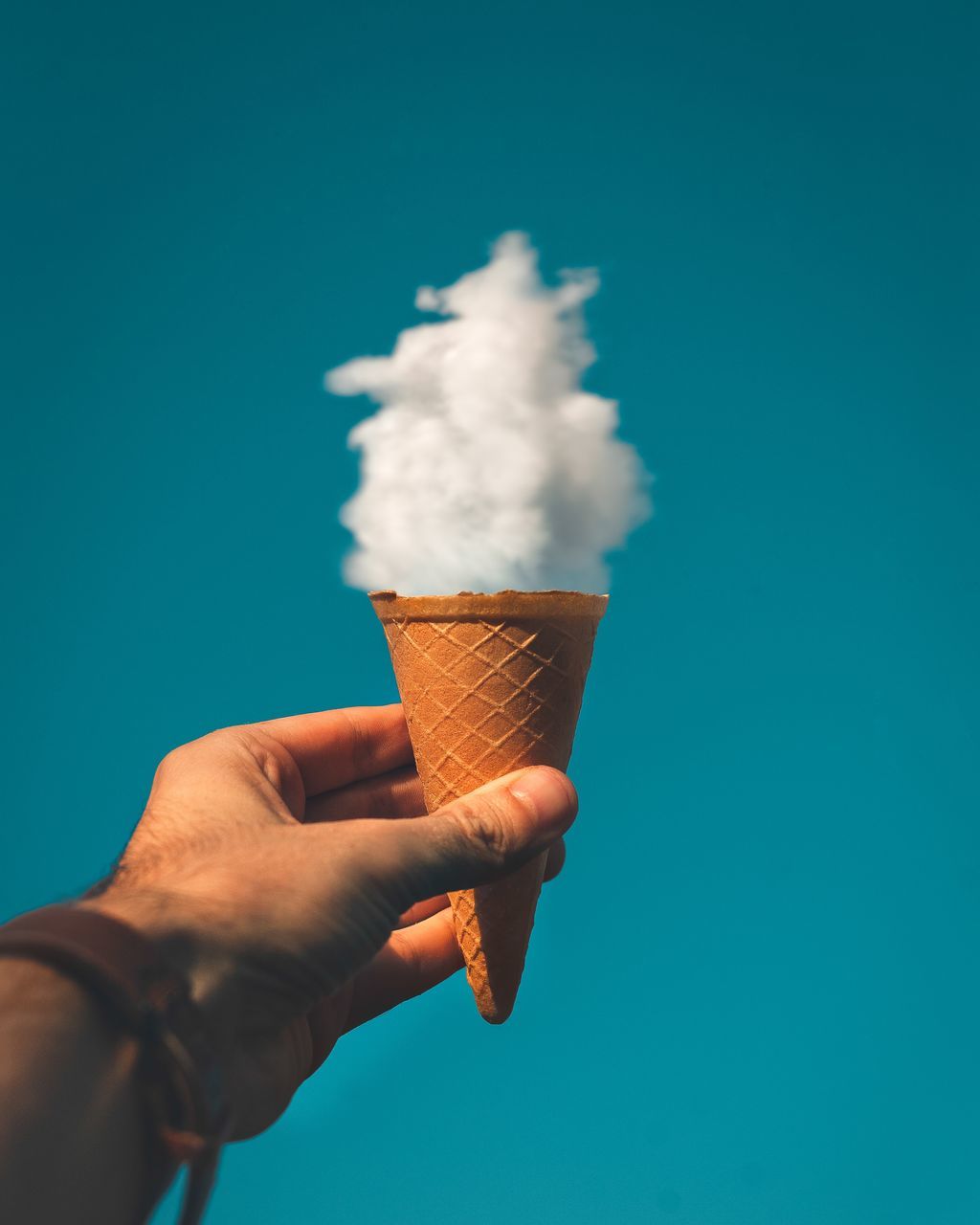 MIDSECTION OF PERSON HOLDING ICE CREAM AGAINST SKY