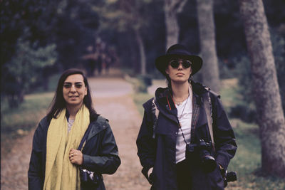 Portrait of young couple standing against trees