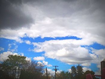 Low angle view of trees against cloudy sky