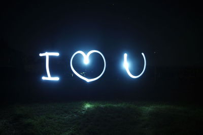 Close-up of illuminated text on grass at night