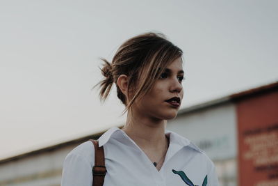 Close-up of young woman standing against sky