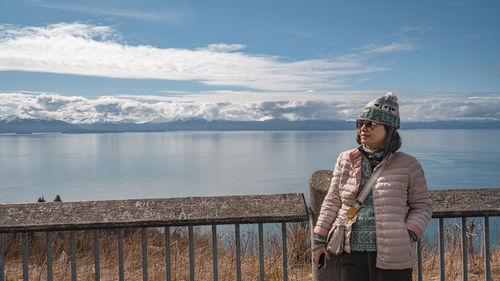 Portrait of woman standing by lake against sky