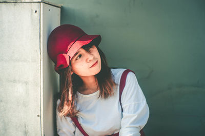 Portrait of beautiful young woman standing against wall