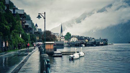 Boats moored in sea by city against sky