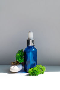 Close-up of green bottle on table against wall