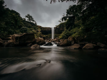 Water flowing through rocks against sky