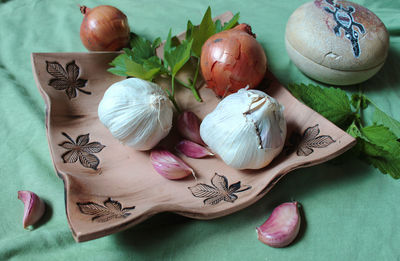 Still life with interesting ceramic plate, onion and garlic on a kitchen table 
