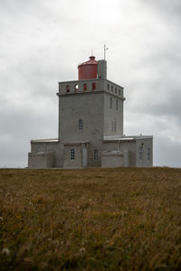 Lighthouse on field against sky