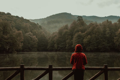 Rear view of woman standing on railing against mountain