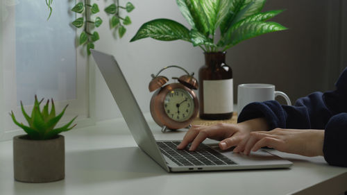 Cropped image of woman using laptop at desk