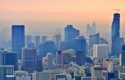 Modern cityscape against sky during sunset