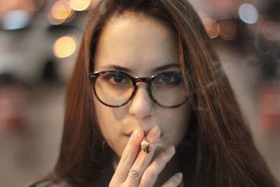 Close-up portrait of young woman smoking cigarette