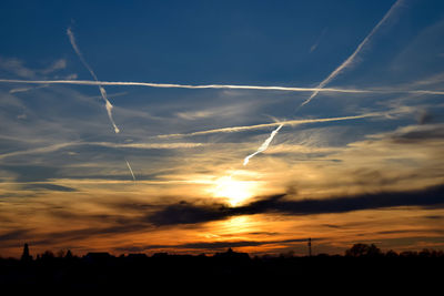 Low angle view of vapor trails in sky during sunset