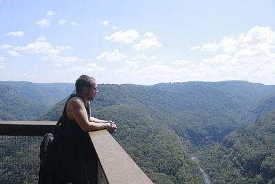 Side view of man looking at mountains against sky