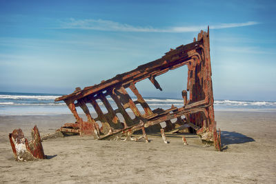 Traditional windmill on beach against sky