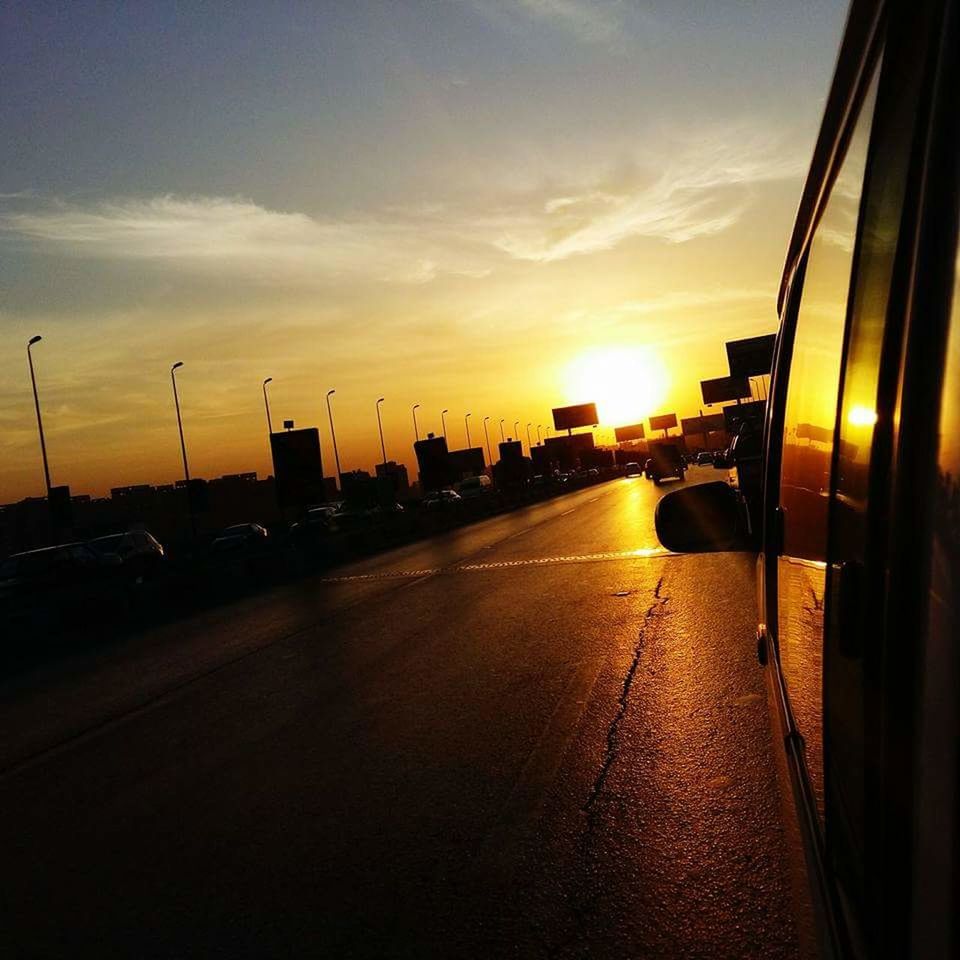 CARS ON ROAD AGAINST SKY AT SUNSET