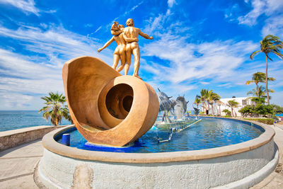 Sculpture by swimming pool against blue sky