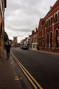 Road by buildings in city against sky