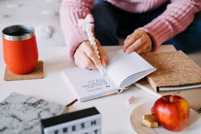 Cropped hand of man writing in book