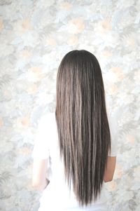 Rear view of woman with long hair against wall