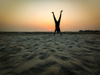 Silhouette person on beach against sky during sunset