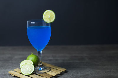 Glass of drink on table against black background