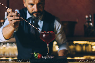 Midsection of man holding wine glass on table