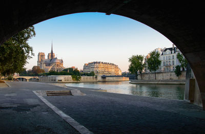 Arch bridge over river amidst buildings in city