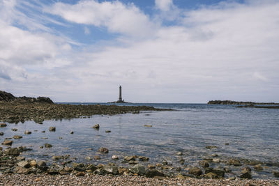 Scenic view of sea against sky with lighthouse in the distance