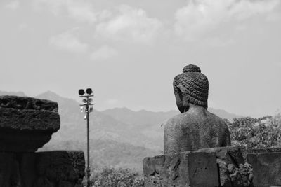 Buddha sculpture at borobudur temple against sky