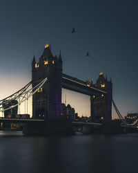 Illuminated bridge over river at night