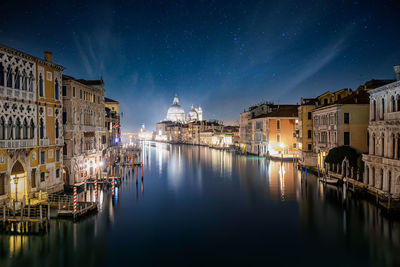 View of canal amidst illuminated buildings in city at night