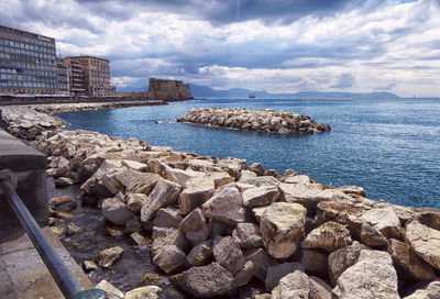 Rocks by sea against sky in city
