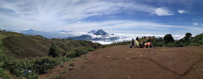 People camping on mountain against sky