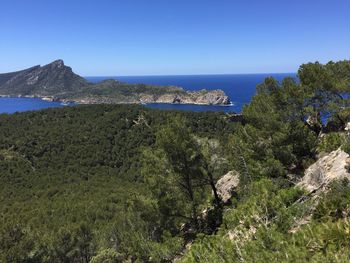 Scenic view of sea and mountains against clear blue sky