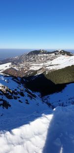 Aerial view of snowcapped mountains against clear blue sky