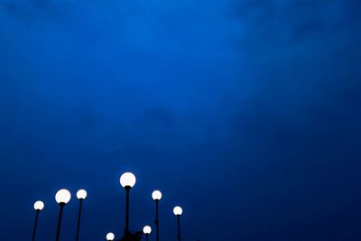 Low angle view of illuminated street light against blue sky