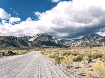 Road leading towards mountains against sky