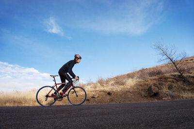 Cyclist riding bicycle on road against sky