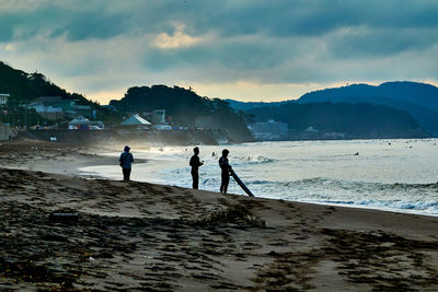 People on beach against sky during sunrise