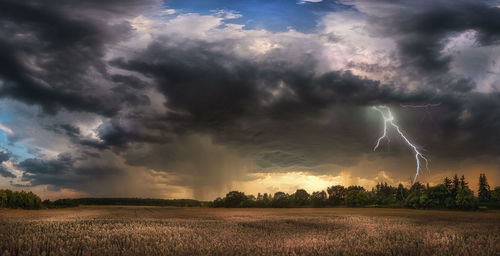 Scenic view of field against storm clouds