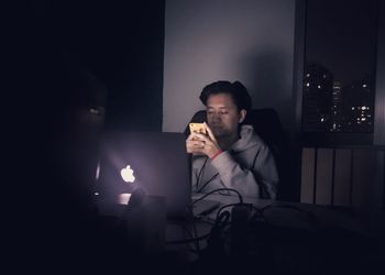 Full length of man sitting in illuminated room