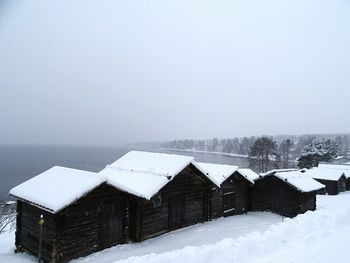 Houses on snow covered landscape against clear sky