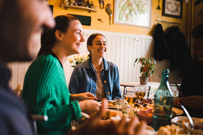 Smiling young women sitting at table in restaurant while enjoying dinner party