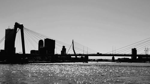 Bridge over river in city against clear sky