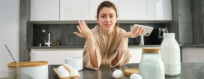 Portrait of young woman using mobile phone at home